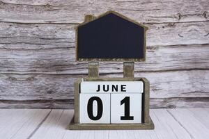 Chalkboard with June 01 date on white cube block on wooden table. photo