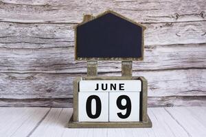 Chalkboard with June 09 date on white cube block on wooden table. photo