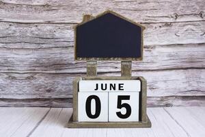 Chalkboard with June 05 date on white cube block on wooden table. photo