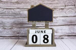 Chalkboard with June 08 date on white cube block on wooden table. photo