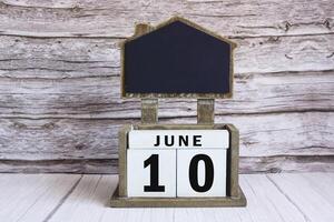 Chalkboard with June 10 date on white cube block on wooden table. photo