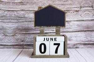 Chalkboard with June 07 date on white cube block on wooden table. photo