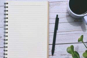 Top view of notepad and pen with cup of coffee photo