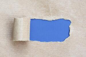 marrón Rasgado papel con azul antecedentes. foto