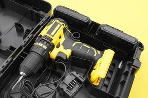 The yellow-black screwdriver on a yellow background, a set of bits. photo