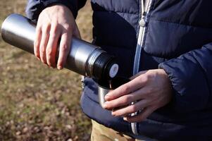 Man's hands pouring fresh hot cocoa from thermos to cup. photo