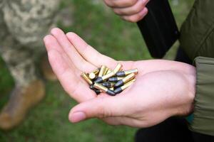 A pile of 22 LR bullets with a round head in the guy's hand. photo