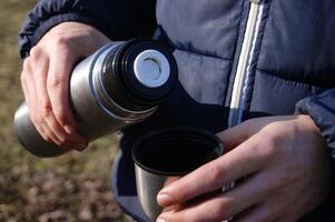 del hombre manos torrencial Fresco caliente cacao desde termo a taza. foto