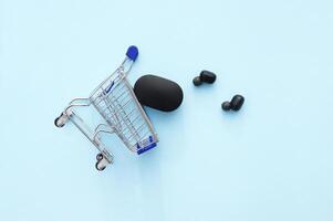 Shopping cart with a black wireless headphones on a blue background. photo