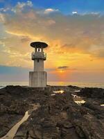 A tranquil seascape with a lighthouse silhouette against a vibrant sunset, perfect for themes of travel and nature photo