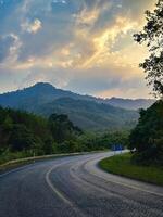 un tranquilo autopista Guías hacia un maravilloso atardecer, flanqueado por lozano verdor y radiante cielo a oscuridad. foto