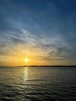 Tranquil sunset over calm waters, showcasing golden hues and peaceful sky, ideal for backgrounds and natural themes photo