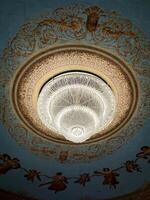 Ornate ceiling with grand chandelier and angelic frescoes in a luxurious interior photo