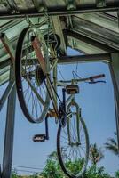 close-up view of a bicycle hanging from the ceiling of a building with a blue sky in the background. photo