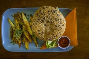 Hamburger with french fries and ketchup on a blue plate with orange napkins photo