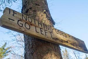 Si nada va bien, luego Vamos izquierda de madera firmar en el bosque adjunto a un árbol. foto