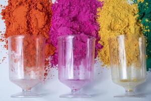 Colorful holi powder with empty glass vase on white background. Top view photo