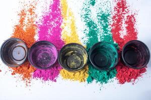 Colorful holi powder on white background and empty black small boxes on top of it. Top view photo