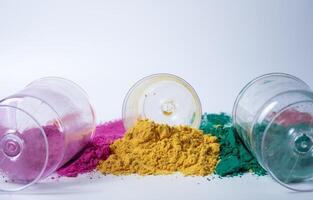 Pink, green, yellow three different color holi powder and glass jars on white background. photo