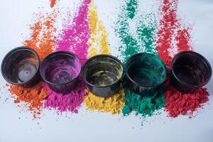 Colorful holi powder on white background and empty black small boxes on top of it photo
