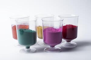 Multicolored holi powder in glass cups on white background. photo