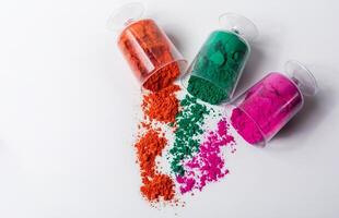 Tricolor Holi powder in plastic containers on white background. photo