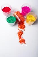 Vertical shot of colorful holi powder in plastic cups on white background with copy space. photo
