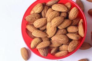 Close up of almonds in a red bowl on a white background. photo
