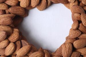 de cerca Disparo de Almendras con corazón conformado blanco espacio en blanco antecedentes. foto