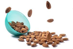 Almonds falling from a blue bowl isolated on white background. clipping path included. photo