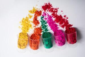 Colorful holi powder in a plastic containers on white background. photo