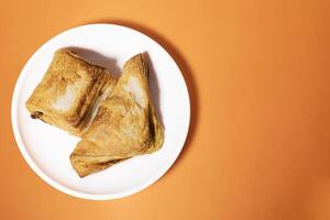 Vegetable puff pastry on a white plate on an orange background. photo