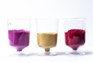 Multicolored holi powder sand in measuring cup isolated on white background. Holi powder is a traditional Indian Festival. photo