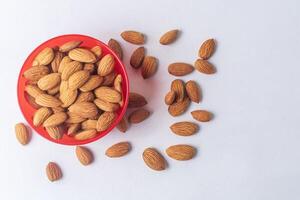 Almond nuts in red bowl isolated on white background, Healthy food concept. photo