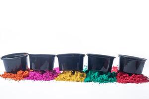 Colorful holi powder in black plastic buckets isolated on white background. Indian Holi festival photo