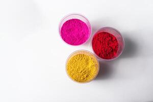 Colorful holi powder in plastic containers isolated on white background. photo