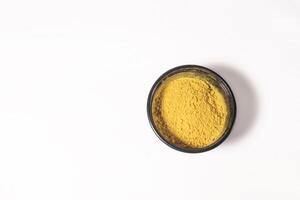 Top view of yellow holi powder in plastic box on white background for Indian festival Holi. Space for text. photo