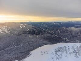 ver de el invierno puesta de sol y cubierto de nieve montañas en Sochi foto