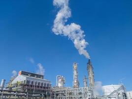 Fertilizer factory producing smoke in chimneys against the backdrop of a bright, cloudy blue sky Photo Formats