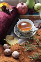 Cozy autumn composition with cup of tea book walnuts and fruits photo