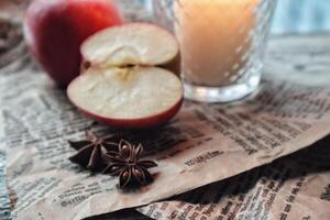 acogedor todavía vida comida fotografía rojo manzanas cortar medio con anís especias en un arte papel siguiente a un vela foto