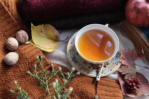 Cozy autumn composition with cup of tea book walnuts and fruits photo