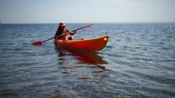 kayak mare donna. contento attraente donna con lungo capelli nel rosso costume da bagno, nuoto su kayak. estate vacanza vacanza e viaggio concetto. video