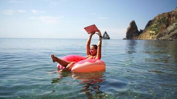 woman floats on an inflatable donut mattress. Happy woman relaxing and enjoying family summer travel holidays travel on the sea. video