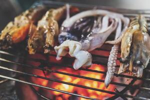 Grilled squid on a cast iron grill over a charcoal grill. photo