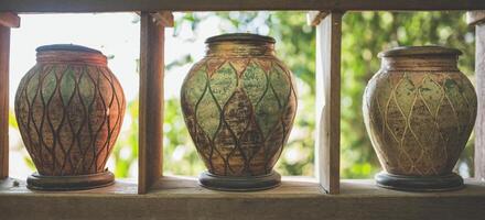 Ancient-style pottery jars are lined up on wooden shelves. photo