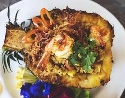 Pineapple fried rice with shredded pork and shrimp wrapped in halved pineapple photo