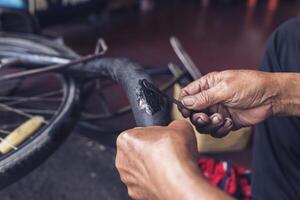 The mechanic patched the inner tube of the bicycle with glue and patch. photo