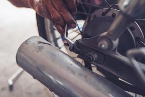 A motorcycle mechanic tightens the tail nut of the rear wheel of the motorcycle. photo