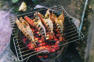 Large prawns are placed on an iron griddle and grilled over a hot coal stove. photo